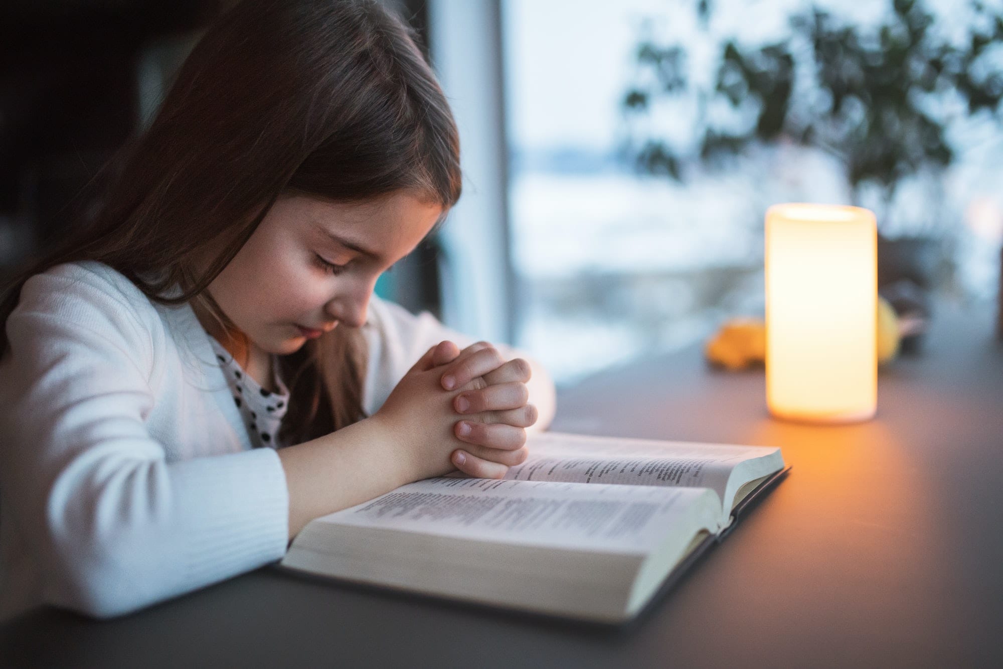A small girl praying at home.